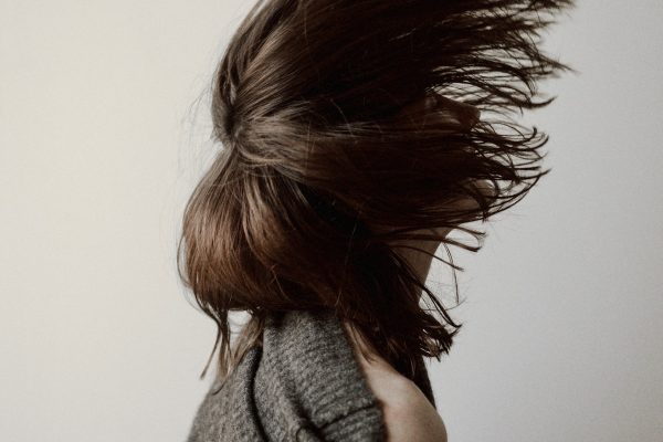 woman in gray sweater standing near white wall