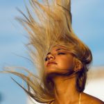 woman wearing yellow halter top whipping hair