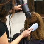 woman holding white and black hair blower